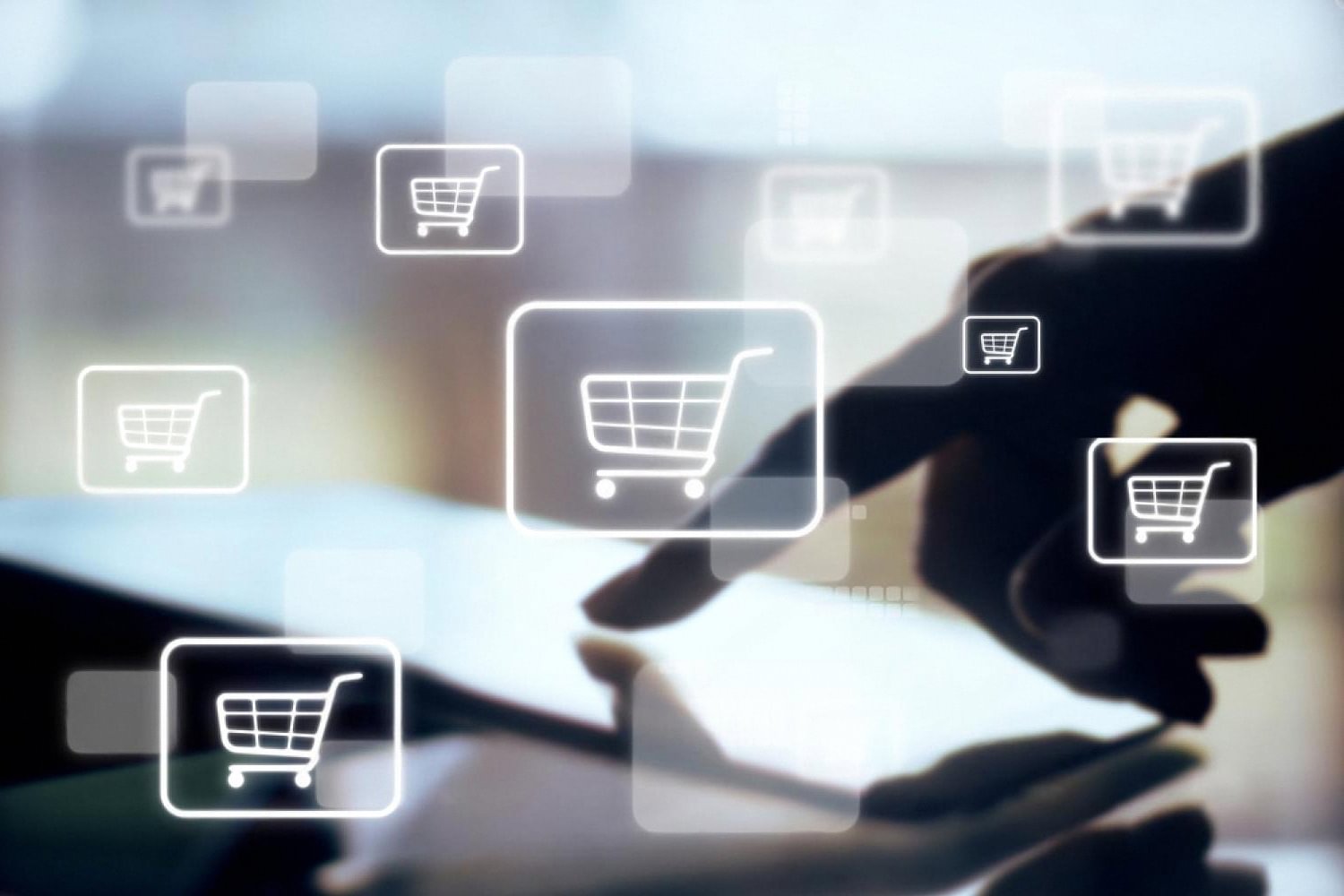 Hand tapping a tablet screen with floating shopping cart icons, representing an online rental marketplace in Dubai